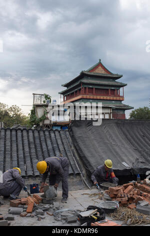 Les travailleurs qui appartiennent à l'autorité de logement de restaurer une vieille maison en face de la tour du tambour à Beijing, Chine. Banque D'Images