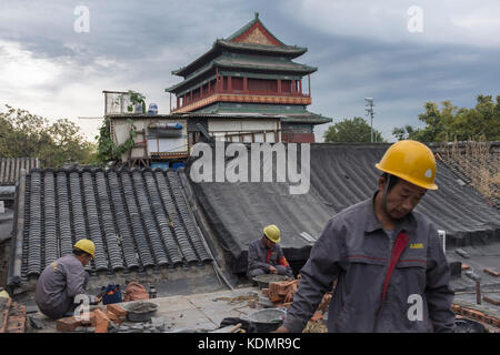 Les travailleurs qui appartiennent à l'autorité de logement de restaurer une vieille maison en face de la tour du tambour à Beijing, Chine. Banque D'Images