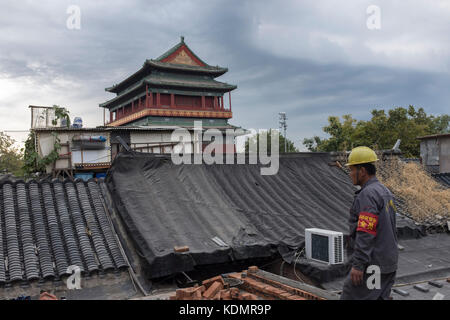 Les travailleurs qui appartiennent à l'autorité de logement de restaurer une vieille maison en face de la tour du tambour à Beijing, Chine. Banque D'Images