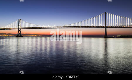 Bay Bridge illuminations reflète dans l'eau par Pier 14, San Francisco. Banque D'Images