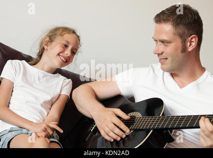 Papa joue de la guitare pour sa fille. Banque D'Images