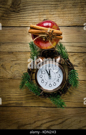 Couronne de noël sapin branches vintage réveil apple brillant rouge cannelle anis étoile sur weathered wood background magic atmosphère confortable. Banque D'Images