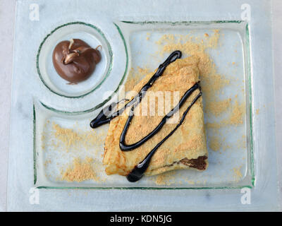 Décorées avec des miettes de crêpes et de chocolat sur plaque de verre avec crème au chocolat Banque D'Images