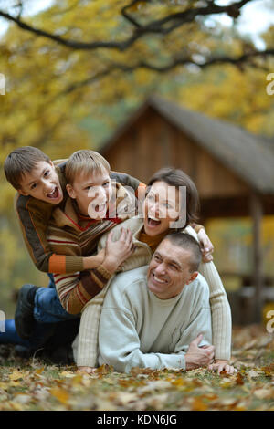 Heureuse famille souriante s'amusant dans la forêt d'automne Banque D'Images