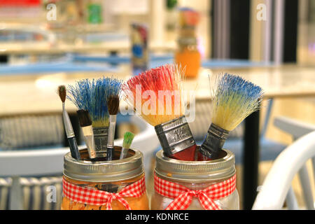 De nombreux pinceaux dans les pots de peinture floue en arrière-plan en classe Banque D'Images