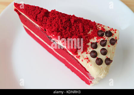 Morceau de gâteau de velours rouge avec de fromage fondu sur une plaque blanche Banque D'Images