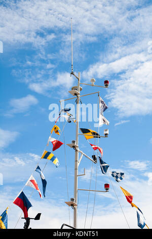 Mât avec signal nautique drapeaux contre le ciel bleu Banque D'Images