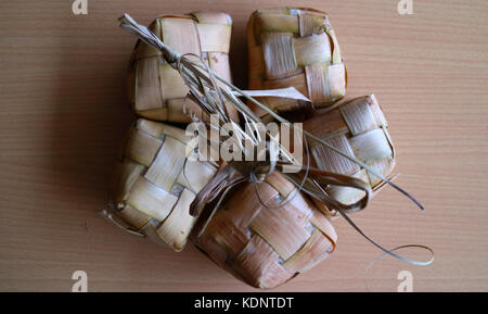 Ketupat, gâteaux de riz traditionnelles. un type de boulette de riz emballés à l'intérieur d'un récipient en forme de losange de tissu de la feuille de palmier et servi sur le sac. Banque D'Images