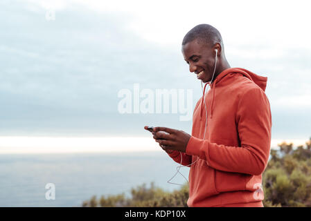 Smiling african man écouter de la musique tandis que dehors le jogging Banque D'Images