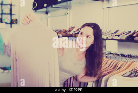 Femme heureuse en choisissant Nouveau chemisier à manches longues vêtements en boutique Banque D'Images