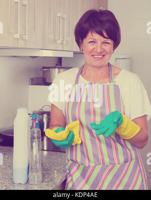 Cheerful woman mature le nettoyage des surfaces et la cuisine dans l'appartement Banque D'Images