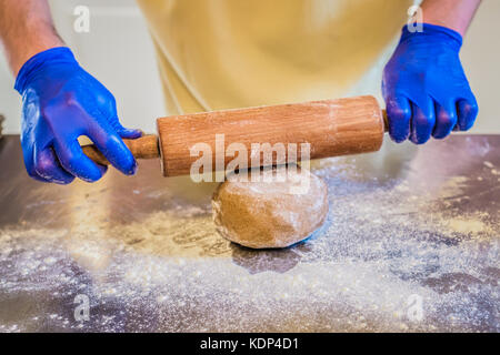 Une entre les mains des hommes dans la préparation des gants avec rouleau à pâte Banque D'Images