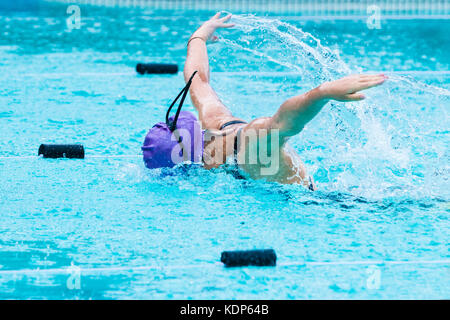 Les jeunes en natation nageuse papillon, élever ses bras vers le haut, avec son visage dans l'eau, à une piscine de l'école Banque D'Images