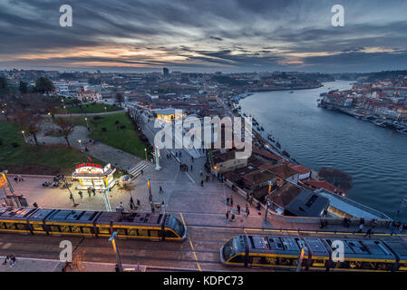 Coucher de soleil sur la ville de Vila Nova de Gaia, Portugal. Vue sur le fleuve Douro Eurotram trains et la station supérieure de Gaia Cable car Banque D'Images