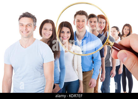 Personne hand holding loupe sur grand groupe de gens heureux se tenant dans la ligne sur fond blanc Banque D'Images