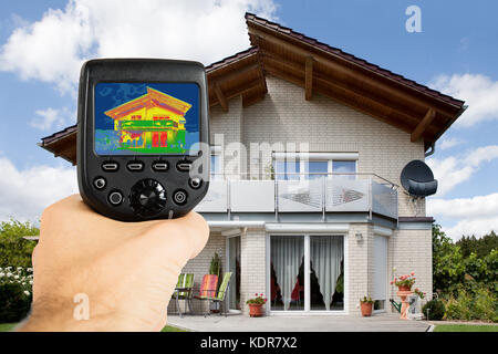 Gros plan d'une personne enregistrant la perte de chaleur de la main avec une caméra infrarouge à l'extérieur de la maison Banque D'Images