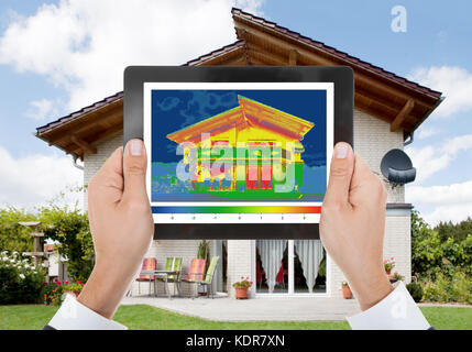 Close-up de la personne la détection de la perte de chaleur à l'extérieur de la Chambre Using Digital Tablet Banque D'Images