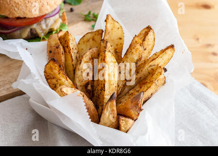 Les pommes de terre cuites au four avec des épices et herbes servi dans du papier blanc - prêt à manger Banque D'Images