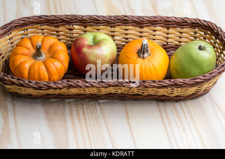 Récolte d'automne de pommes,poires et citrouilles dans un panier en osier. Banque D'Images