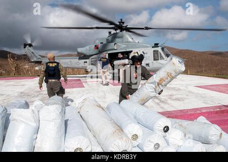 Les Marines et les volontaires américains déchargent des bâches et des fournitures d'urgence d'un hélicoptère UH-1Y Venom Super Huey du corps des Marines des États-Unis pendant les efforts de secours au lendemain de l'ouragan Irma le 11 septembre 2017 à John, Îles Vierges américaines. Banque D'Images