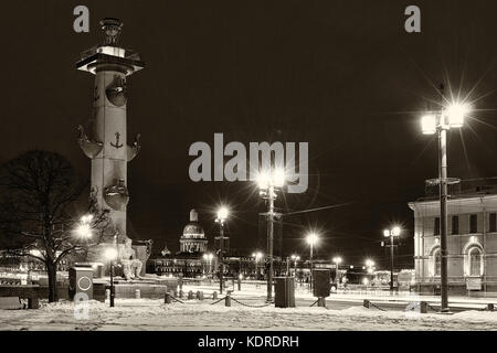Llandmark et spot touristique à St Petersbourg, Russie : pointe de l'île Vassilievski par nuit d'hiver avec la colonne rostrale et la cathédrale Saint Isaac Banque D'Images