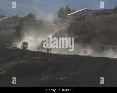 Soirée dans un village de montagne : sur une route poussiéreuse reviennent chez eux, les rayons de soleil dans un brouillard de poussière et silhouette chiffres, Himalaya. Banque D'Images