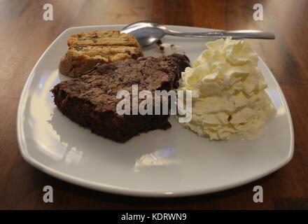 Brownie au chocolat à moitié mangé avec de la crème sur le côté Banque D'Images