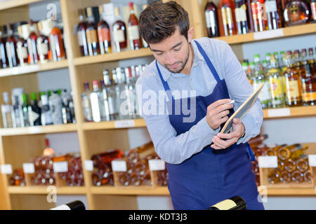 Vendeur smiling man wearing apron in wine store Banque D'Images