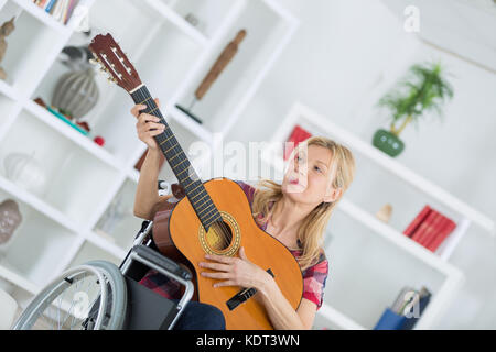 Mobilité dame jouant de la guitare acoustique Banque D'Images