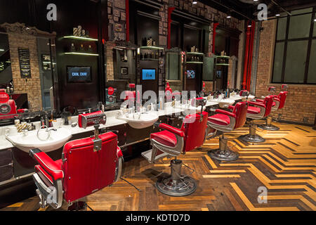 À l'intérieur d'une boutique de coiffeur pour hommes modernes à Londres, en Angleterre. Présente un mélange de mobilier vintage à la recherche et la télévision numérique, et agrémentées de parquet. Banque D'Images