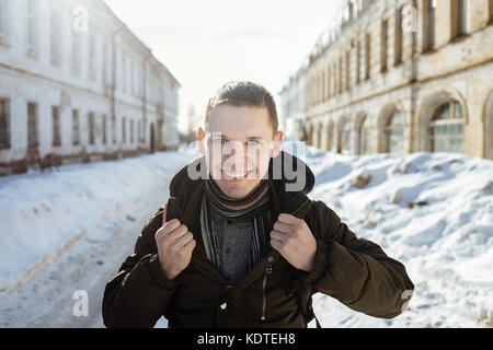 Un sourire heureux homme portant une écharpe tendance fourrure posant dans la ville. Banque D'Images