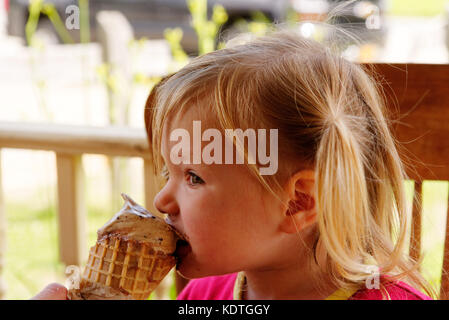 Une petite fille (3 ans) de manger une glace au chocolat Banque D'Images