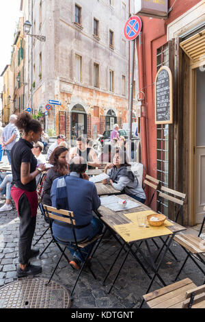 Les gens assis à des tables de restaurant dans une rue de Rome, Italie Banque D'Images