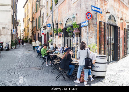 Les gens assis à des tables de restaurant dans une rue de Rome, Italie Banque D'Images