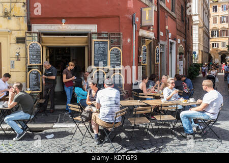 Les gens assis à des tables de restaurant dans une rue de Rome, Italie Banque D'Images