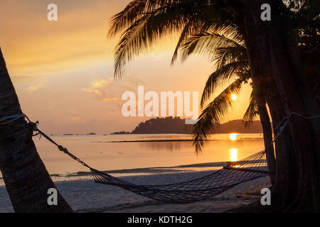 Magnifique lever de soleil sur plage de sable sur l'île de Bintan en Indonésie avec silhouette de hamac et cocotiers avec copie espace. Banque D'Images