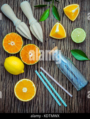 Presse-agrumes et jus de citrons frais .Le flacon en verre, de la chaux et des oranges sur table en bois miteux avec télévision. Banque D'Images