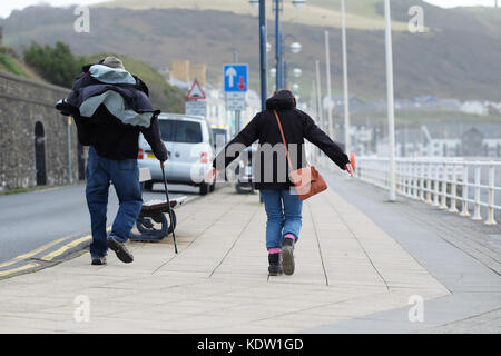 Aberystwyth, Ceredigion, pays de Galles, Royaume-Uni. 16 oct, 2017. uk weather. un couple trouve cela difficile car ils marcher le long de la promenade dans les forts vents à Aberystwyth, sur la côte ouest du pays de galles comme approches ophelia tempête au large de la mer d'Irlande avec les vent est supérieure à 50 mi. photo steven mai / alamy live news Banque D'Images