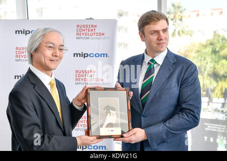 (171016) -- CANNES, 16 oct. 2017 (Xinhua) -- Masahiko Tomonaga (G), vice-ministre de la coordination des politiques du ministère japonais des Affaires intérieures et des Communications, au nom du Japon, pays d'honneur du MIPCOM 2016, offre un cadeau à Mikhail Mamonov, directeur général de la promotion du commerce international du Russian Export Center, à Cannes, France, le 16 oct. 2017. Le MIPCOM 2017 (marché international des programmes de communication), qui s'étend sur quatre jours et qui met en lumière les produits de communication russes cette année, a débuté lundi. (Xinhua/Chen Yichen) (lrz) Banque D'Images