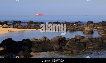 Petite baie tranquille avec un grand navire conteneur rouge à l'horizon au format paysage with copy space Banque D'Images