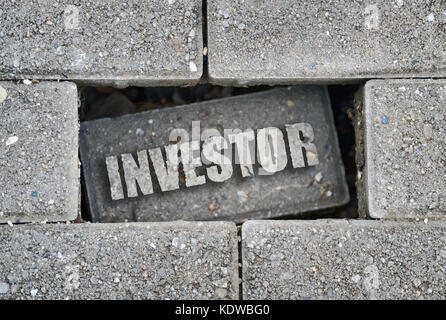 Investisseurs mot écrit sur une brique brisée sur le trottoir Banque D'Images