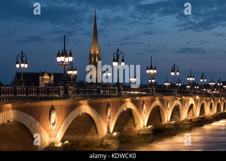 Pont de pierre enjambant le fleuve Garonne au crépuscule avec basilique Saint-Michel au-delà, Bordeaux, Aquitaine, France Banque D'Images