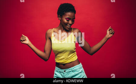 African woman dancing sur fond rouge. Cheerful fashion model dancing en studio. Banque D'Images