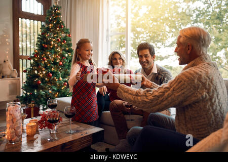 Cadeau à donner grand-père petite fille pour Noël et nouvel an. Family sitting in living room l'échange des cadeaux de Noël. Banque D'Images