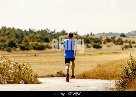 Retour d'exécution sur l'athlète masculin runner road entre domaine de l'herbe jaune Banque D'Images