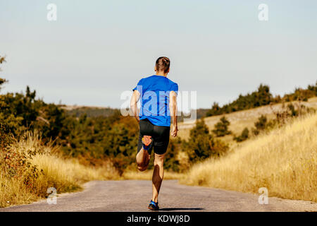 Retour homme dynamique d'exécution sur road runner automne herbe jaune de champ Banque D'Images