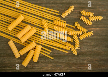 Sélection des matières style italien spaghetti pâtes non cuites et les fusilli rigatoni avec copie de l'espace sur un fond de bois vert Banque D'Images