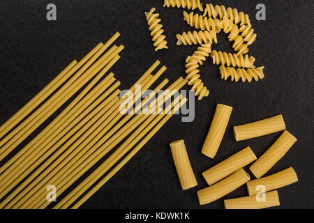 Sélection des matières style italien spaghetti pâtes non cuites et les fusilli rigatoni avec copie espace sur fond noir Banque D'Images