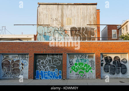 Portes de garage et un bâtiment dégradé en milieu urbain couvert de graffitis et tags, Montréal, Québec, Canada Banque D'Images