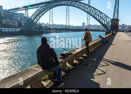 Hommes de pêche dans le fleuve Douro à Porto, Portugal. Dom Luis I Pont entre les villes de Vila Nova de Gaia (à gauche) et Porto en arrière-plan Banque D'Images